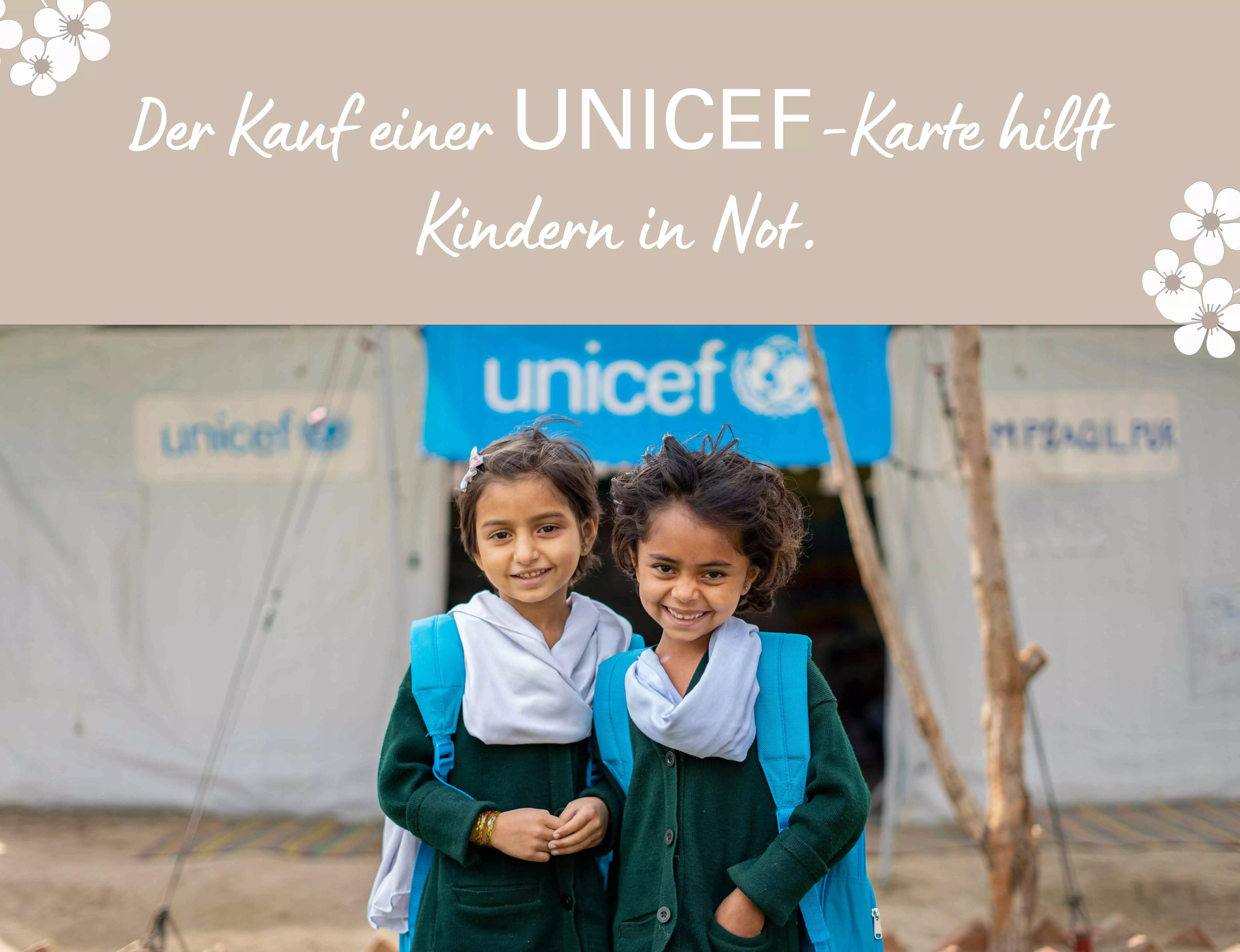 Foto von zwei nebeneinanderstehenden Mädchen, die vor einem UNICEF-Zelt lächeln