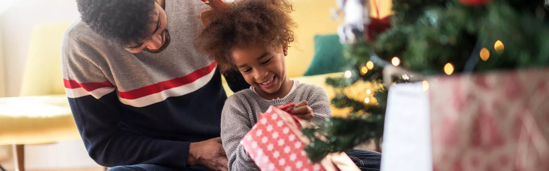 Weihnachtsgrüße: Papa und Tochter packen ein Weihnachtsgeschenk aus