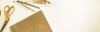 Sprüche zur Taufe: Goldene Schere, Stifte, Papierblock auf weißem Untergrund