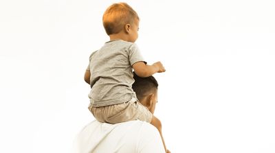 Sprüche zur Taufe: kleiner Junge sitzt auf den Schultern eines Erwachsenen
